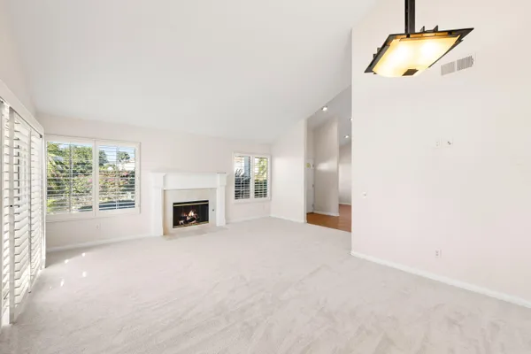 a view of an empty room with a fireplace and a window