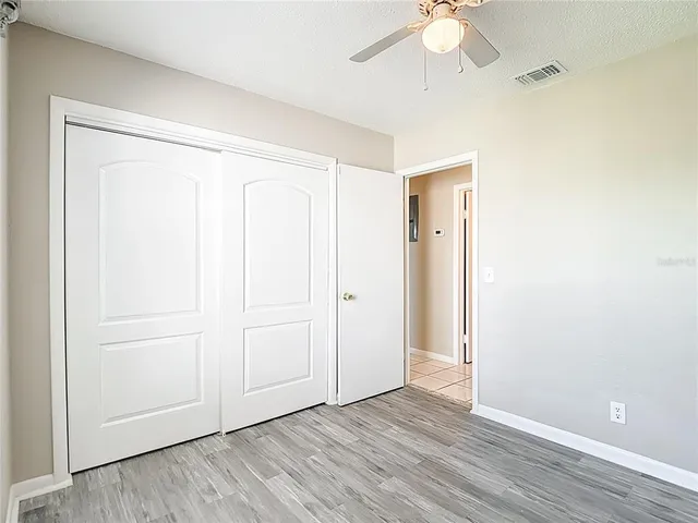 an empty room with wooden floor closet and windows