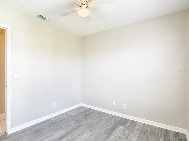 an empty room with wooden floor and fan