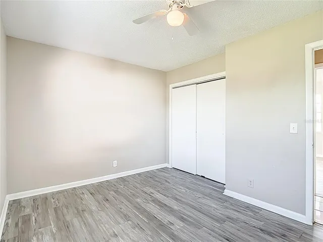 an empty room with wooden floor and fan