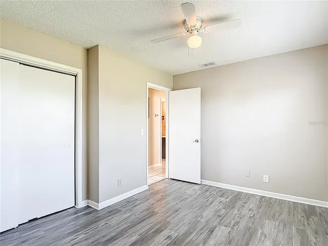 an empty room with wooden floor and ceiling fan