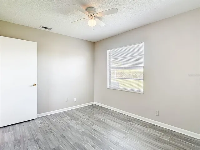 a view of empty room with wooden floor and fan