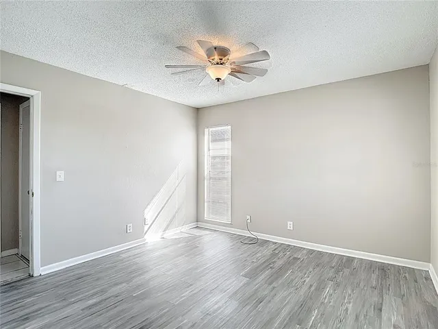 an empty room with wooden floor and ceiling fan