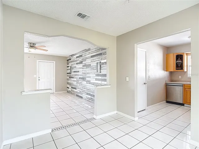a view of a kitchen with white cabinets and empty room