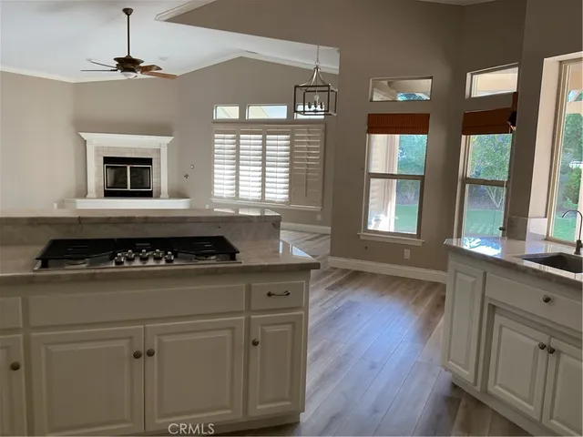 a kitchen with a stove a sink wooden floor and a window