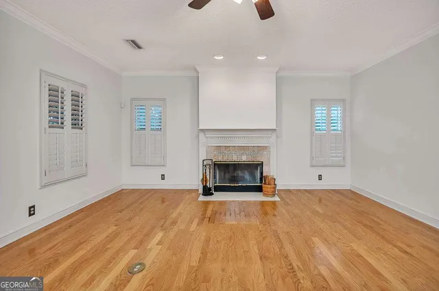 a view of an empty room with wooden floor fireplace and a window