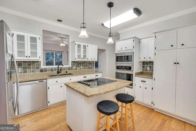 a kitchen with stainless steel appliances granite countertop a stove a sink and a refrigerator with white cabinets