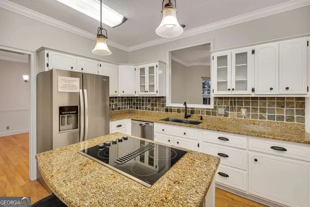 a kitchen with granite countertop a sink a counter space appliances and cabinets
