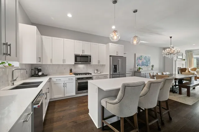 a large kitchen with kitchen island white cabinets and stainless steel appliances