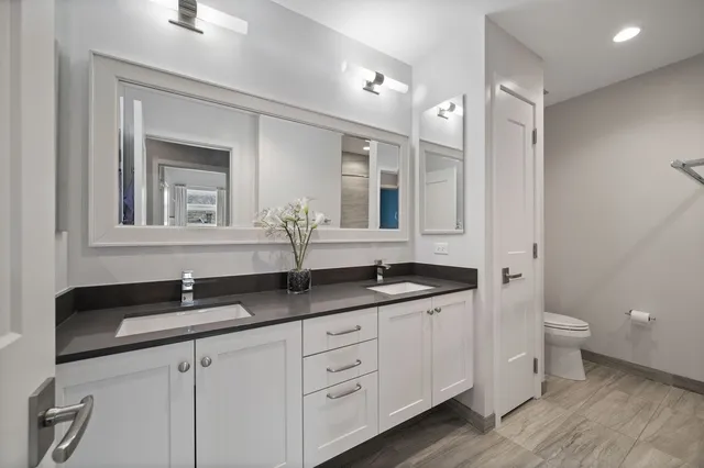 a bathroom with a granite countertop sink a large mirror a toilet and a vanity