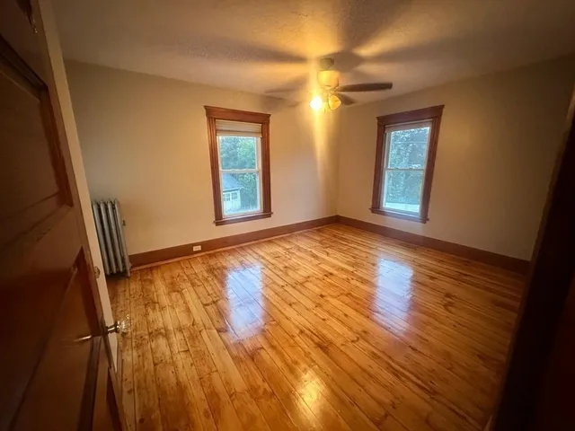 a view of an empty room with window and wooden floor