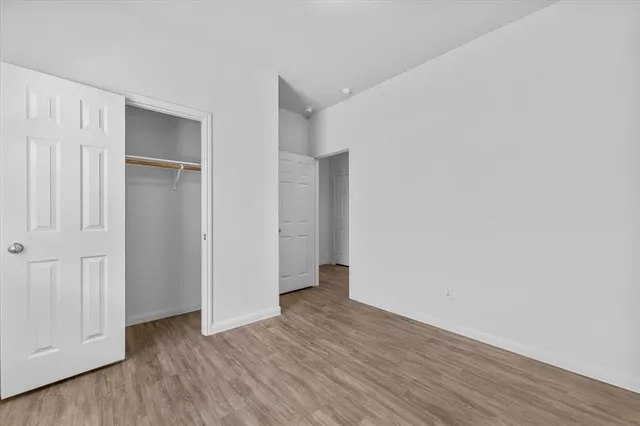 a view of an empty room with wooden floor and closet