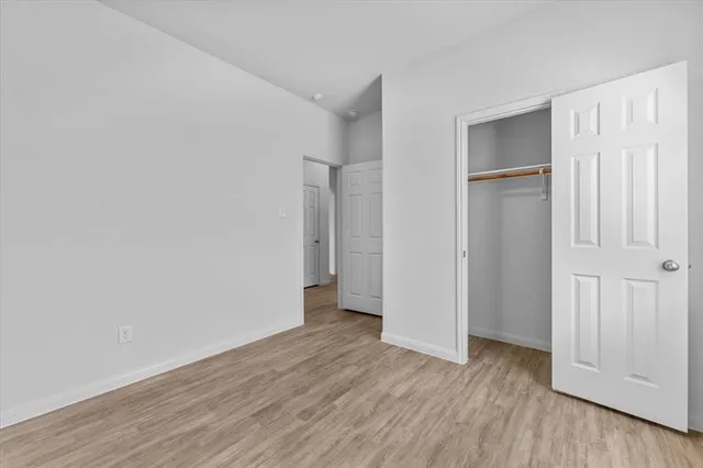 a view of an empty room with closet and wooden floor