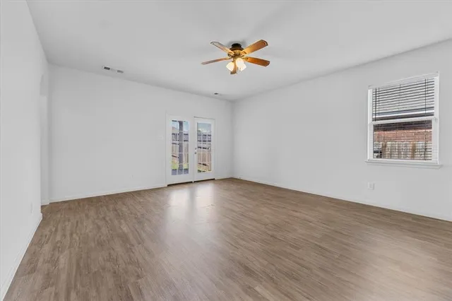 a view of an empty room with window and wooden floor
