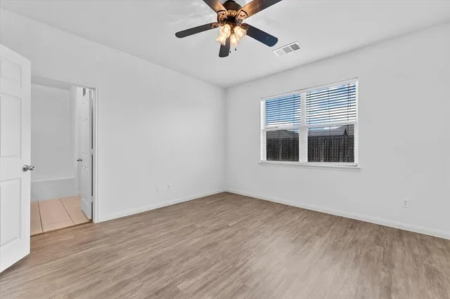 a view of an empty room with window and wooden floor