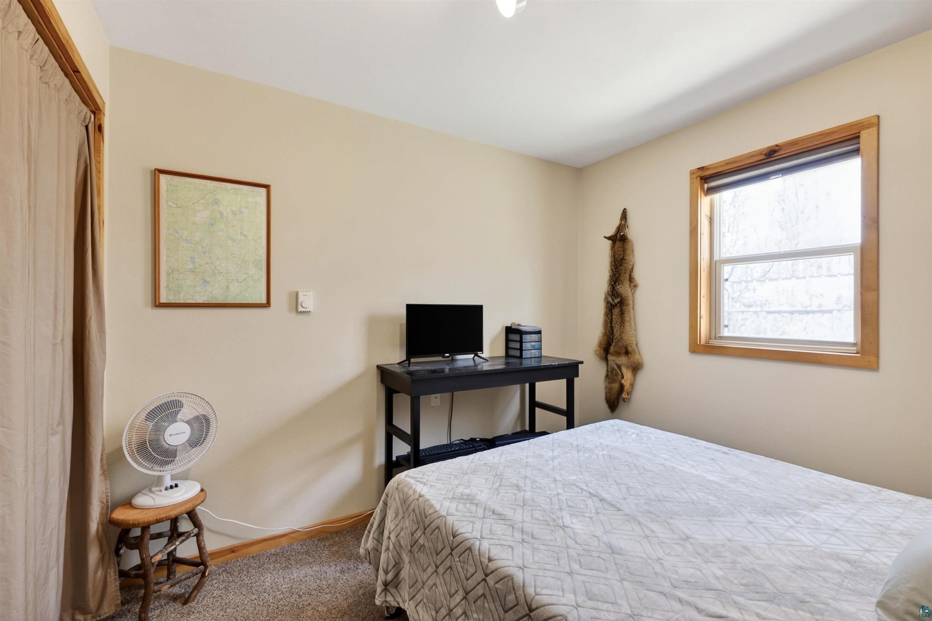 12235 East Crooked Lake Road Gordon, WI 54838 - Photo 20 of 48 Carpeted room featuring a single window with wood trim, neutral wall paint, and a built-in closet with a fabric curtain