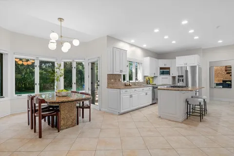 a kitchen with kitchen island granite countertop wooden cabinets a dining table and chairs