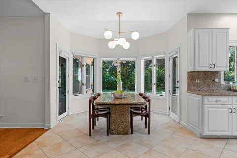 a dining room with wooden floor a chandelier a wooden table and chairs