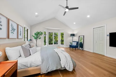 a spacious bedroom with a large bed and a flat tv screen