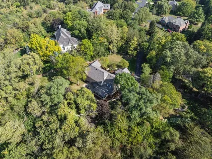 an aerial view of residential house with outdoor space and trees all around
