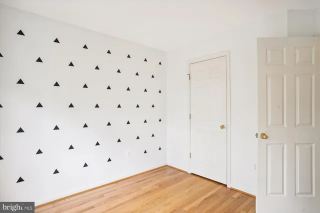 an empty room with wooden floor chandelier fan and windows