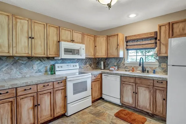 a kitchen with cabinets appliances a sink and a window