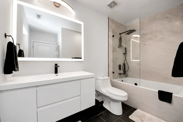 a bathroom with a toilet sink a mirror and shower