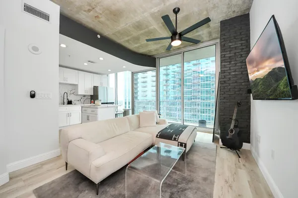 a living room with furniture a large window and a chandelier