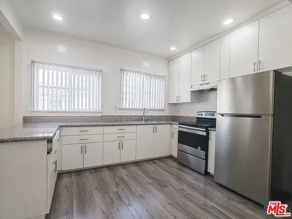 a kitchen with granite countertop white cabinets and white stainless steel appliances
