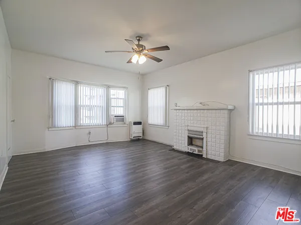 an empty room with wooden floor fireplace and windows