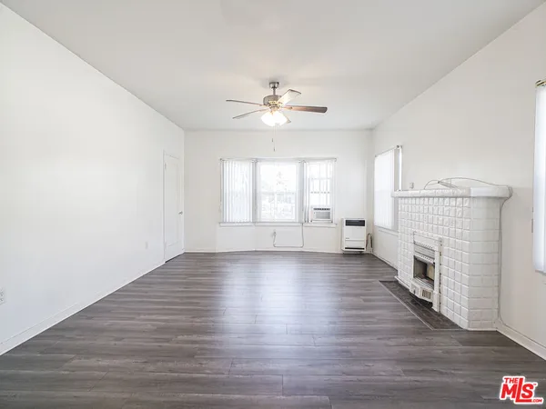 an empty room with fireplace wooden floor and windows