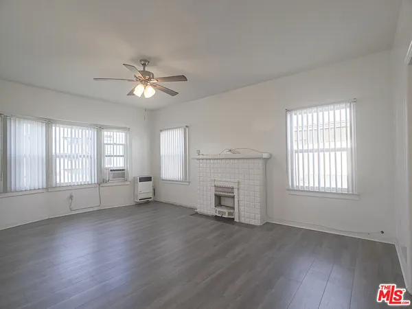 an empty room with wooden floor fireplace and windows