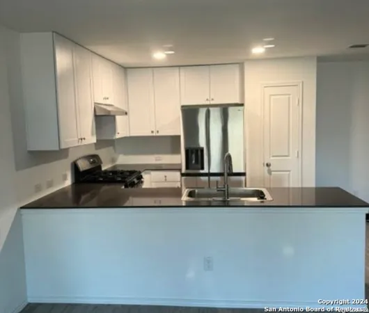 a kitchen with kitchen island granite countertop a sink and a stove