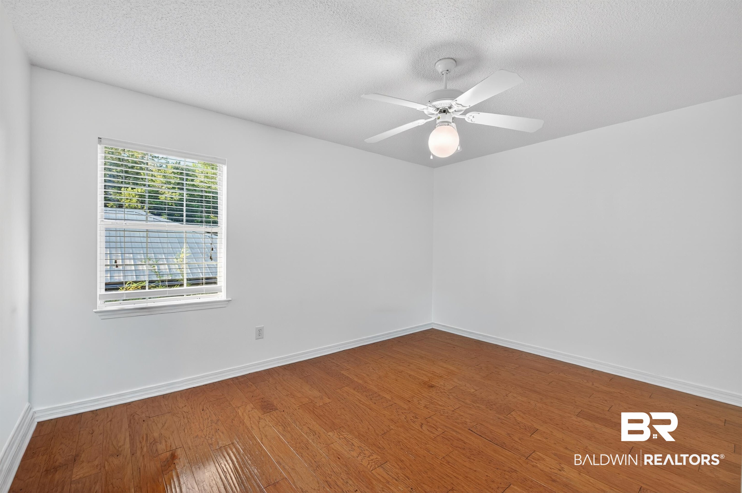 9624 North Bay Street Foley, AL 36535 - Photo 32 of 59 Spacious room featuring wood-finish flooring, a ceiling fan with integrated lighting, white walls, and a window with blinds