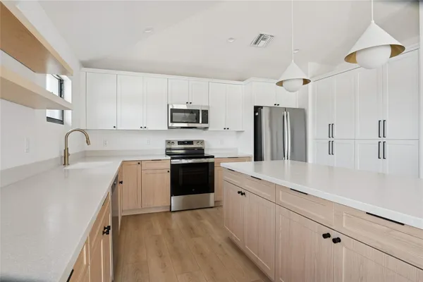 a kitchen with kitchen island a sink stainless steel appliances and cabinets