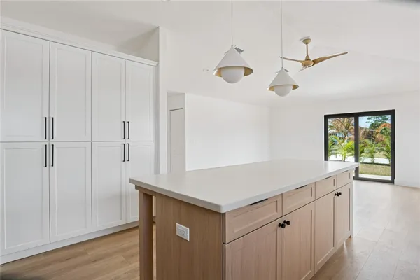 a large white kitchen with a sink and dishwasher a refrigerator with wooden floor