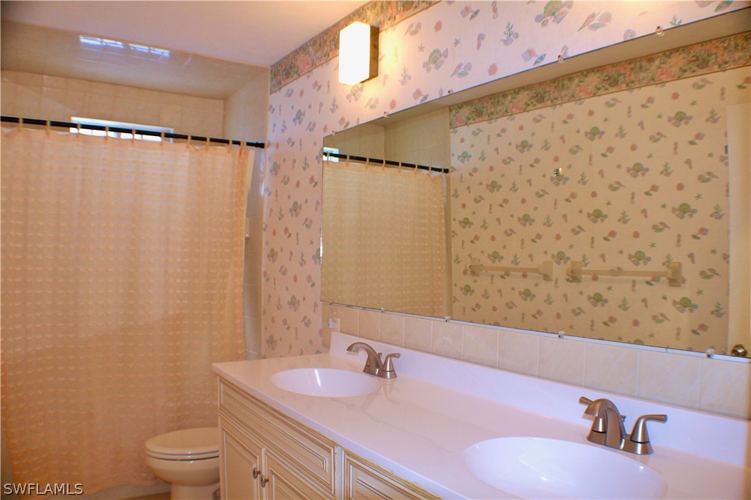 12210 Shawnee Road Fort Myers, FL 33913 - Photo 13 of 28 a bathroom with a granite countertop sink toilet a mirror and shower curtain