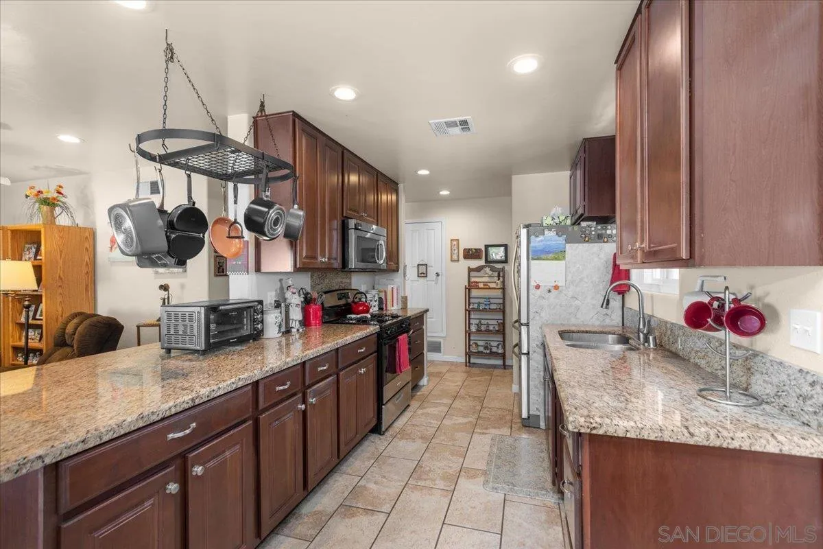 9254 Shadow Hill Road Santee, CA 92071 - Photo 16 of 34 a kitchen with stainless steel appliances kitchen island granite countertop a sink and cabinets
