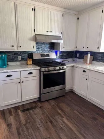 a kitchen with granite countertop white cabinets and appliances