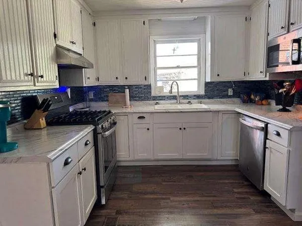 a kitchen with cabinets appliances a sink and a window