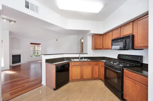 a kitchen with stainless steel appliances granite countertop a sink a stove cabinets counter space and a window