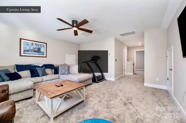 a living room with furniture a rug and a ceiling fan
