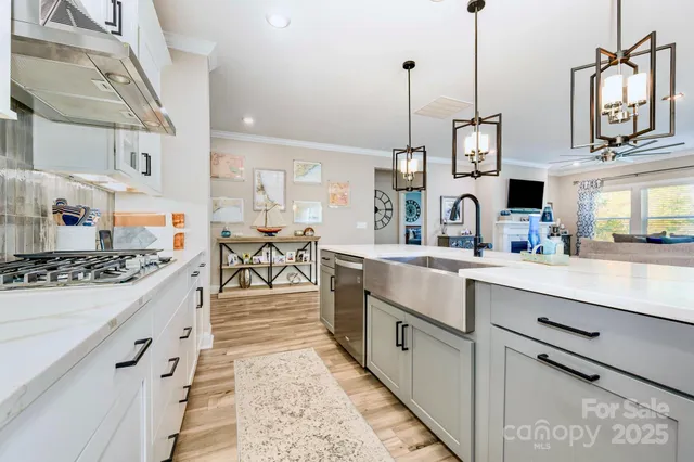 a open kitchen with stainless steel appliances granite countertop a stove a sink dishwasher and white cabinets with wooden floor