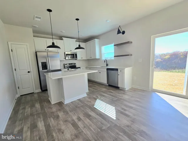 a kitchen with stainless steel appliances granite countertop a sink a stove a refrigerator and island with wooden floor