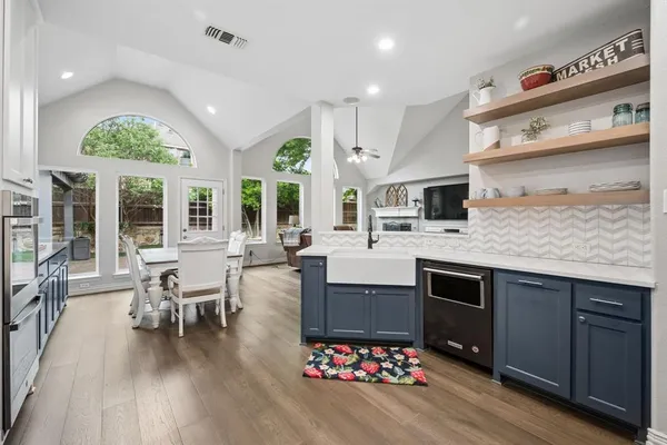 a kitchen with stainless steel appliances granite countertop a stove top oven a sink dishwasher and a dining table with wooden floor
