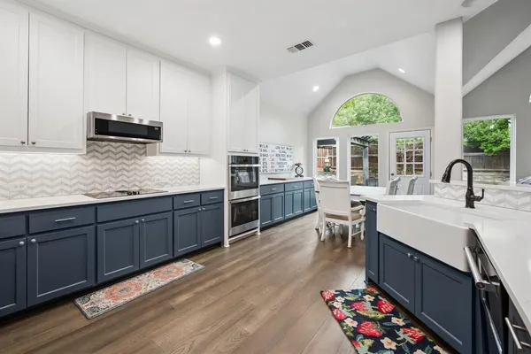 a kitchen with stainless steel appliances a stove a sink a oven a dining table and chairs