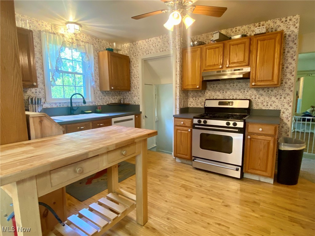 1568 Sunview Road Cleveland, OH 44124 - Photo 10 of 50 Kitchen featuring wallpapered walls, stainless steel gas stove, dark countertops, light wood-type flooring, and under cabinet range hood