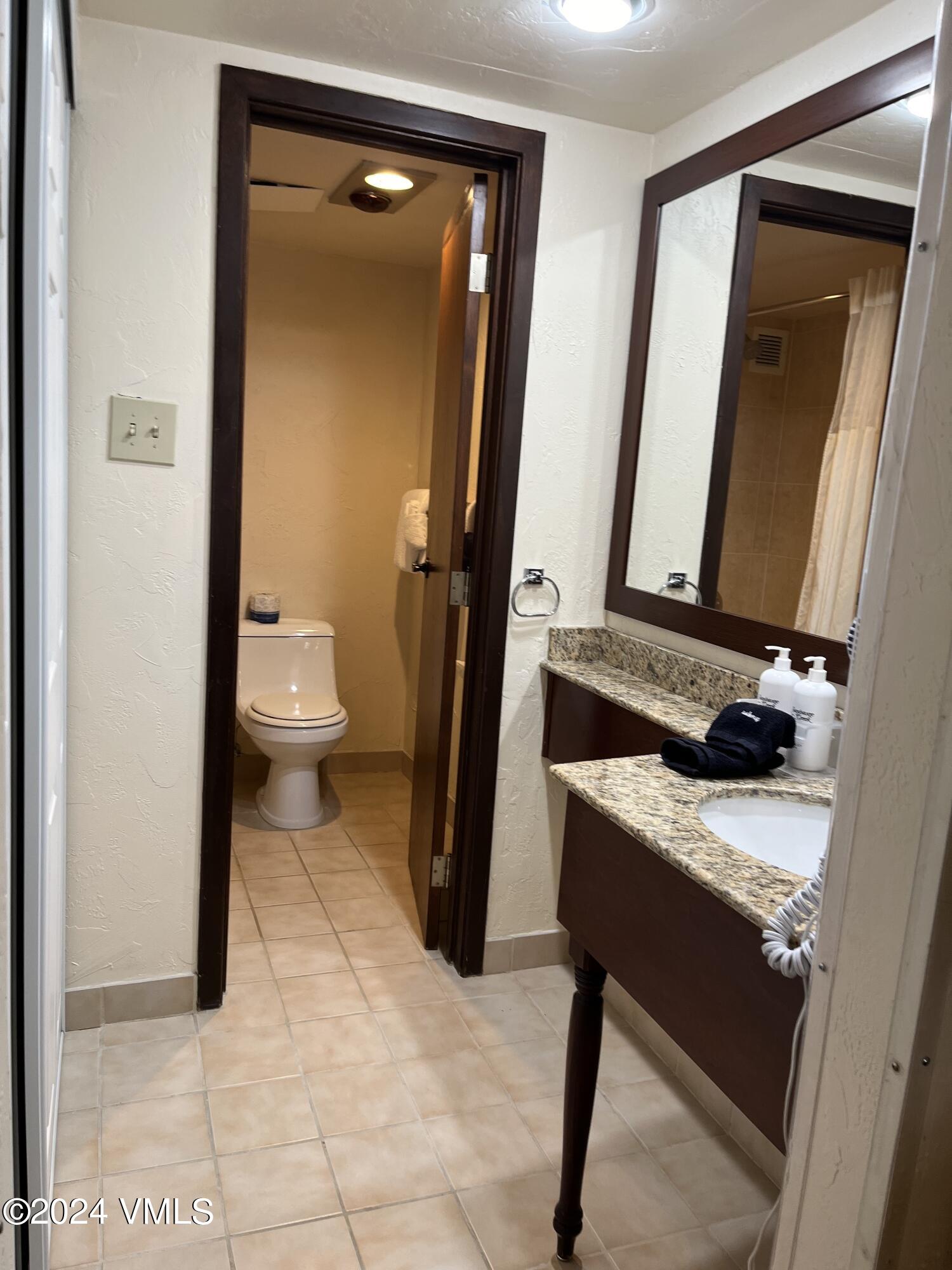 1020 Vail View Drive, Unit 141139 Vail, CO 81657 - Photo 4 of 20 a bathroom with a granite countertop sink a toilet and mirror