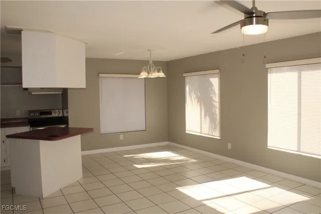 a view of an empty room with window and chandelier fan