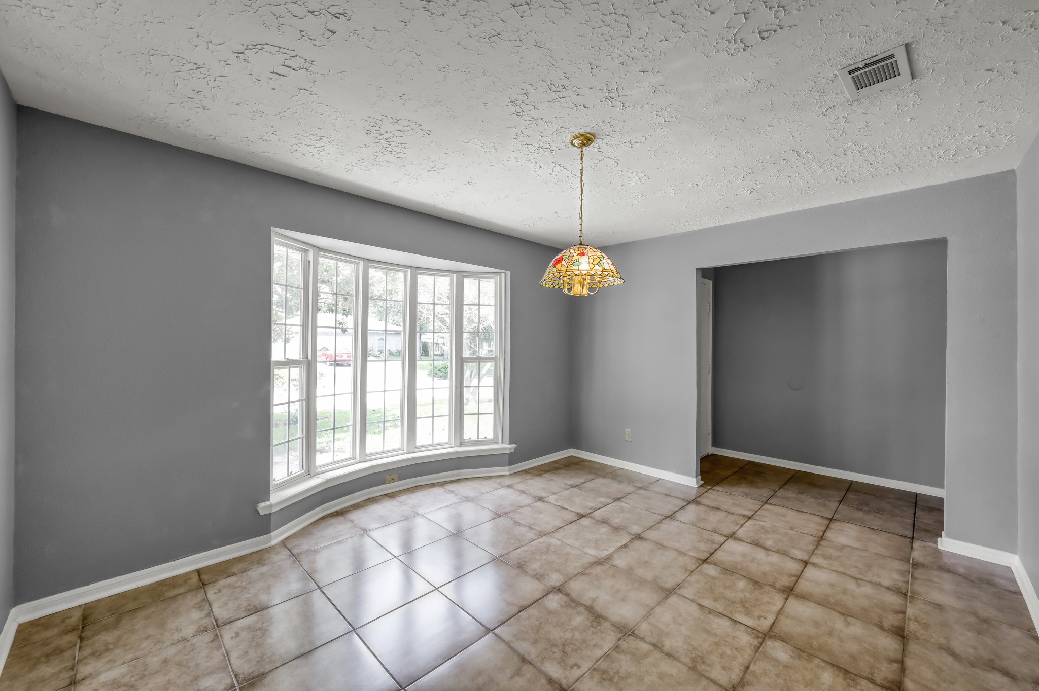 4314 Enchantedgate Drive Spring, TX 77373 - Photo 9 of 47 This room features a large bay window for ample natural light, tiled flooring, and a decorative hanging light fixture. It's ideal for a dining or sitting area.